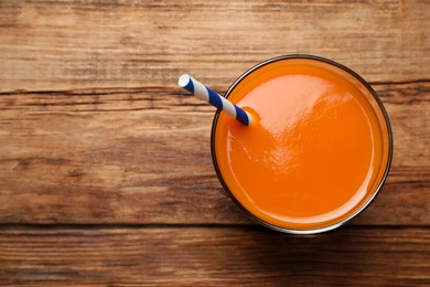 Photo of Glass of tasty carrot juice on wooden table, top view. Space for text