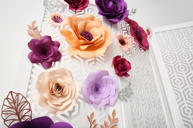 Photo of Ornate white folding screen with floral decor on light background, low angle view. Beautiful photo zone