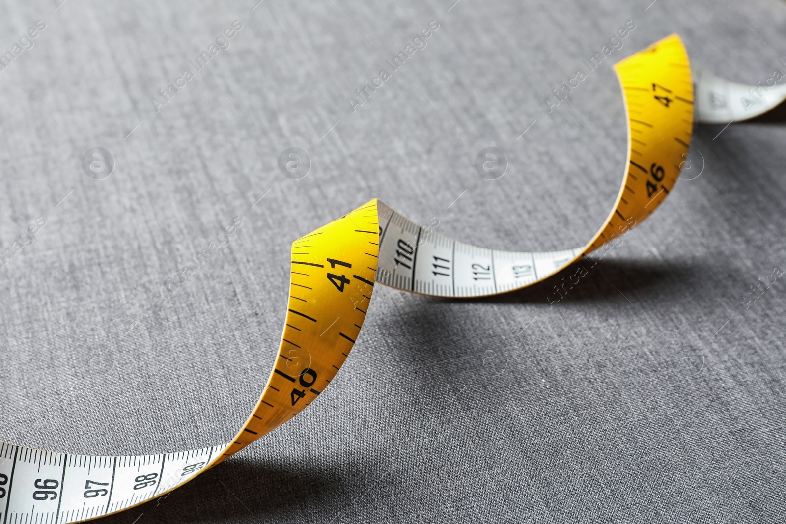 Photo of Measuring tape on grey fabric. Tailoring equipment