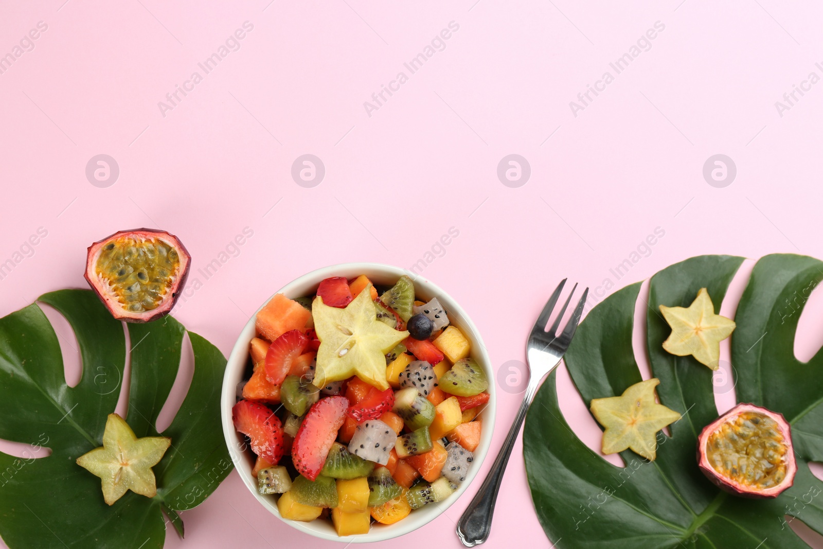 Photo of Flat lay composition with delicious exotic fruit salad on pink background. Space for text