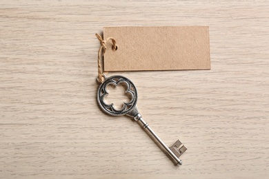 Photo of Key with blank tag on wooden table, top view. Keyword concept