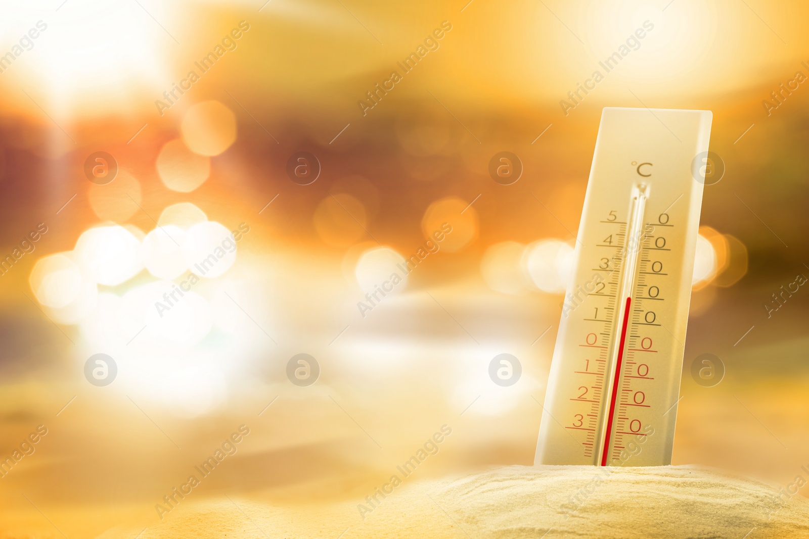 Image of Thermometer in sand on beach during sunny summer day