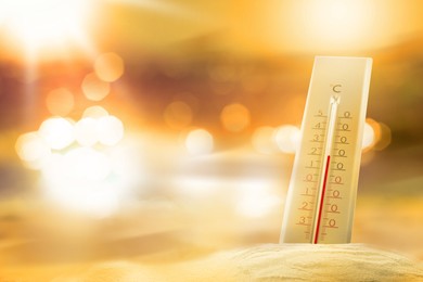 Thermometer in sand on beach during sunny summer day