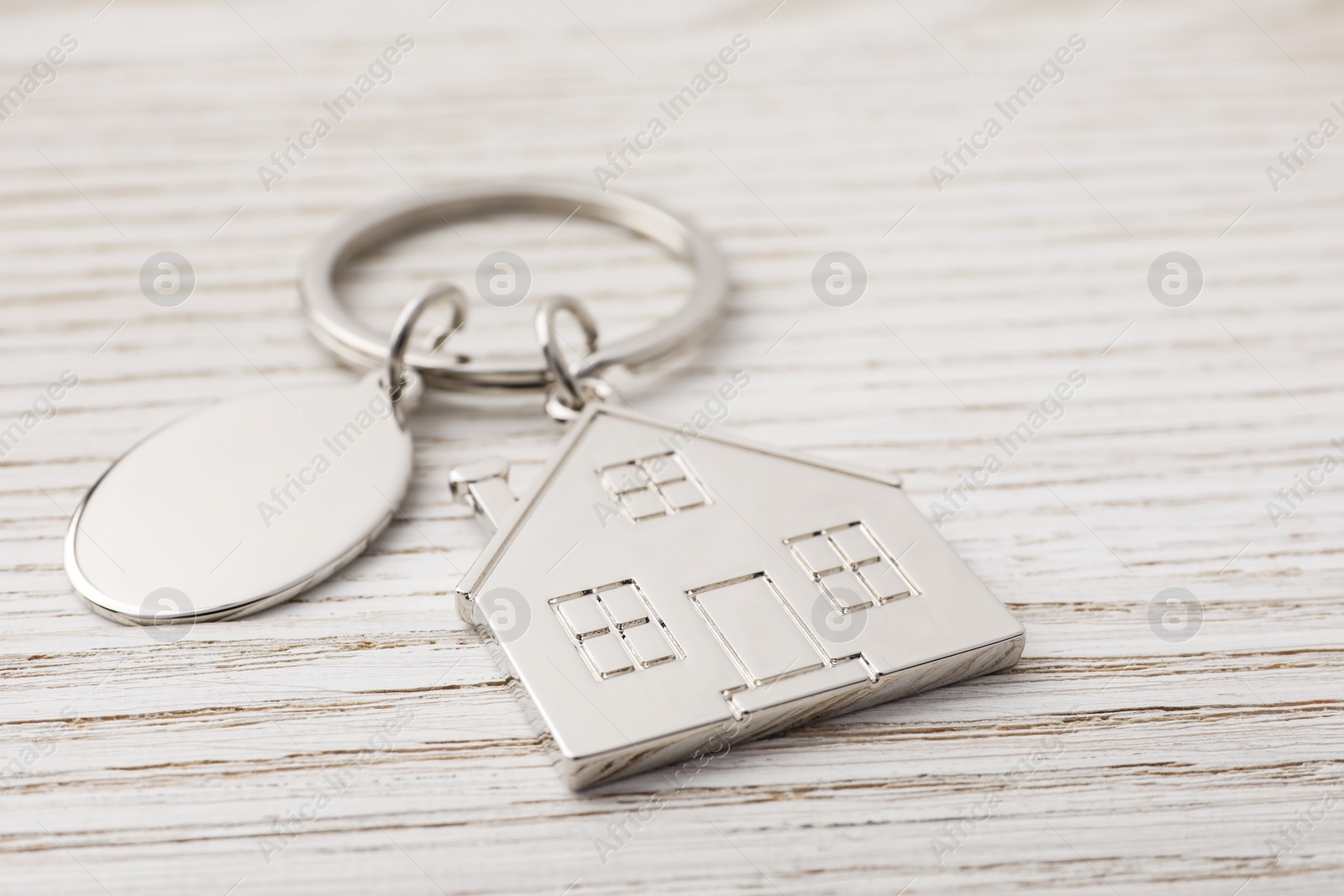 Photo of Metallic keychains with key ring on light wooden background, closeup