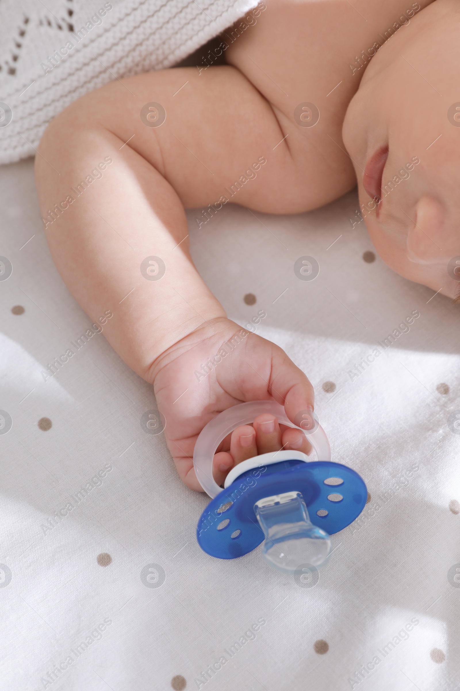 Photo of Little baby with pacifier in bed, closeup