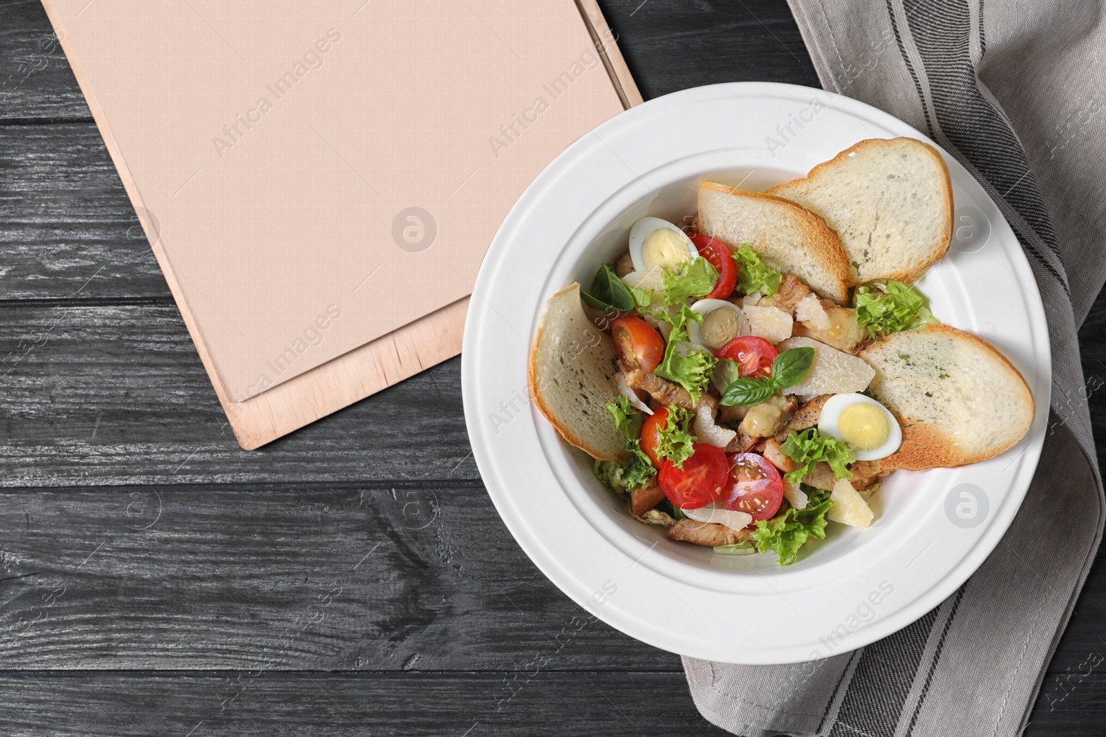 Photo of Plate with delicious fresh salad and menu on table, top view