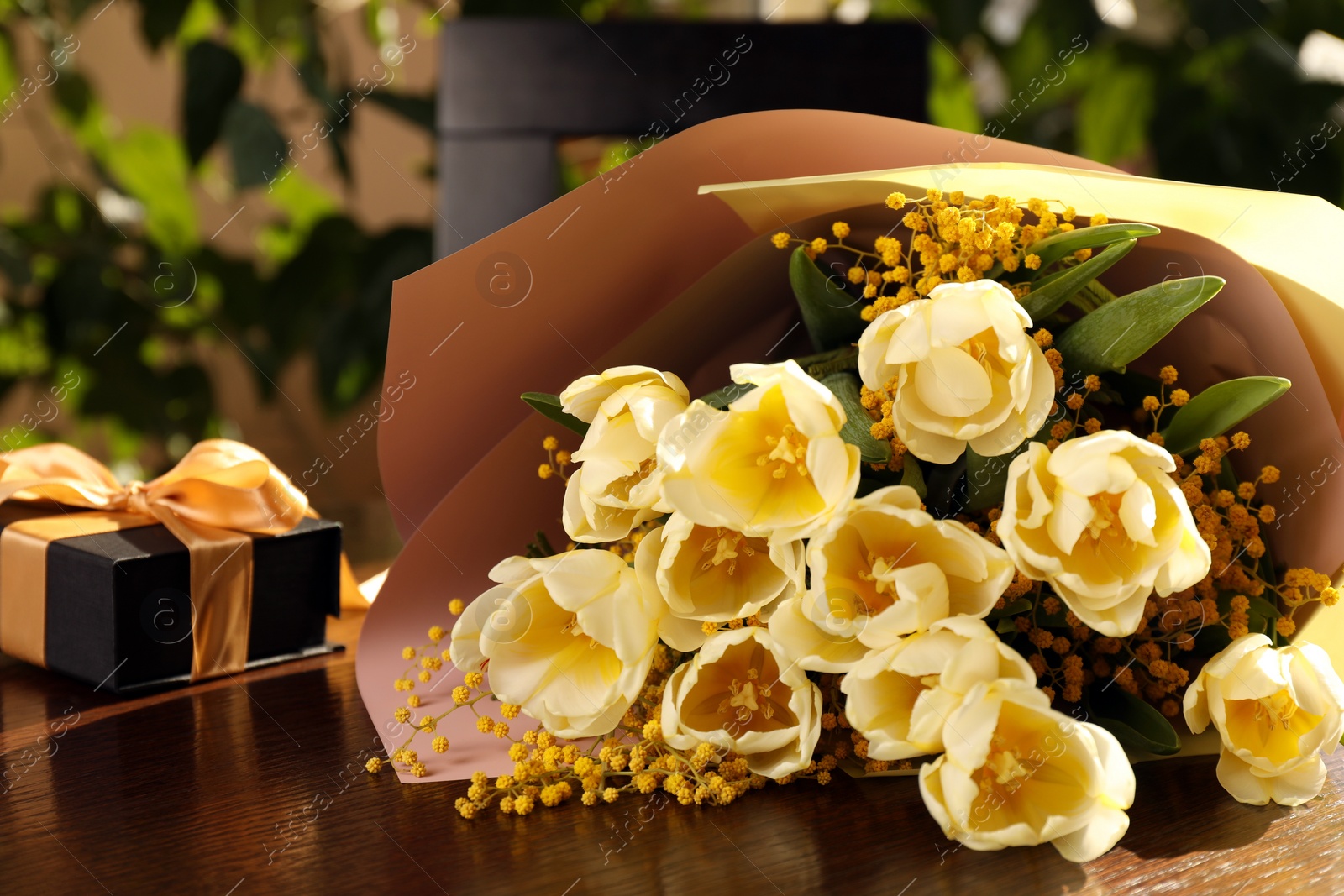 Photo of Bouquet with beautiful tulips, mimosa flowers and gift box on wooden table indoors