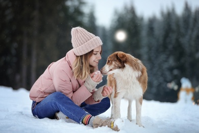 Photo of Young woman with dog near forest. Winter vacation