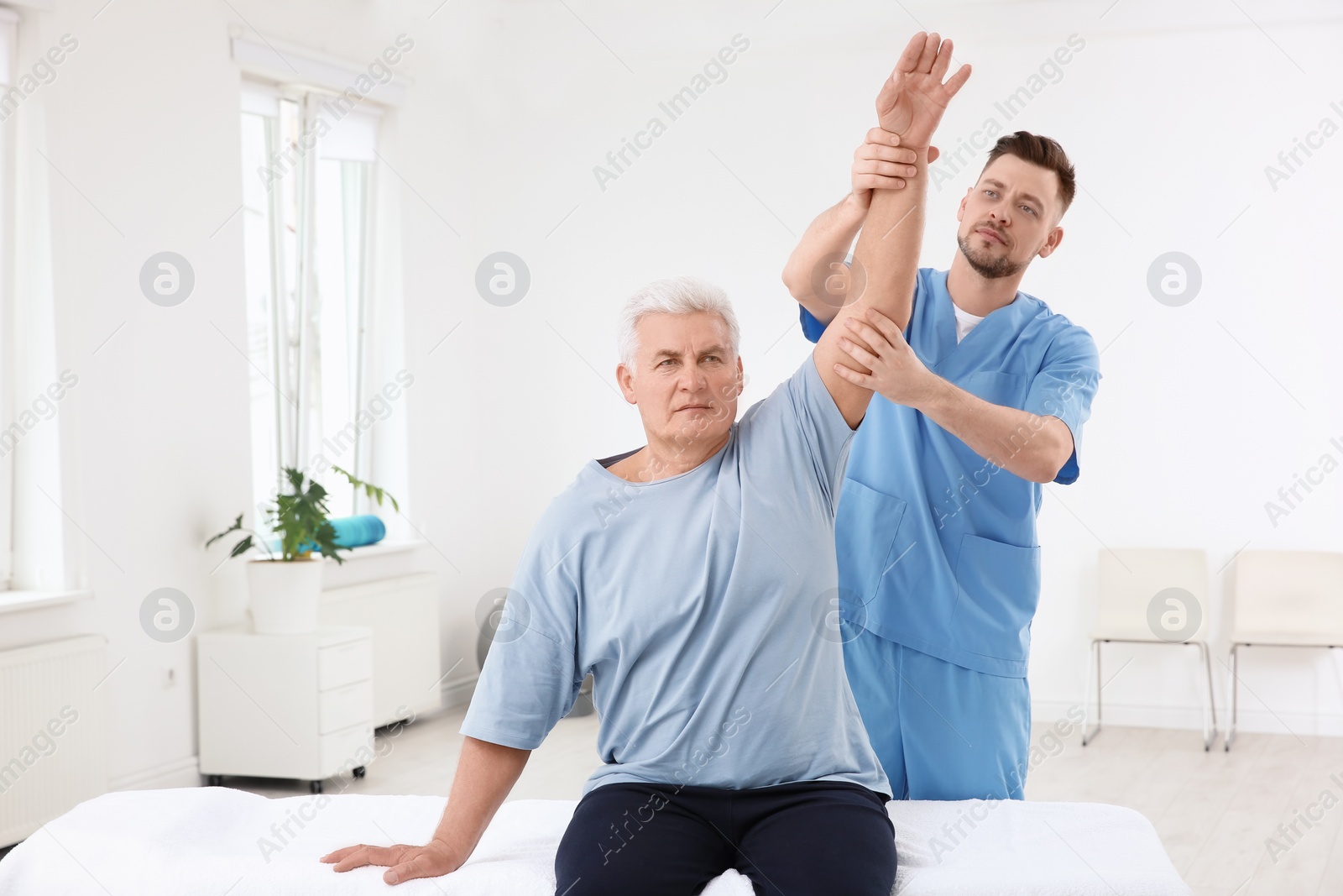 Photo of Young physiotherapist working with senior patient in clinic