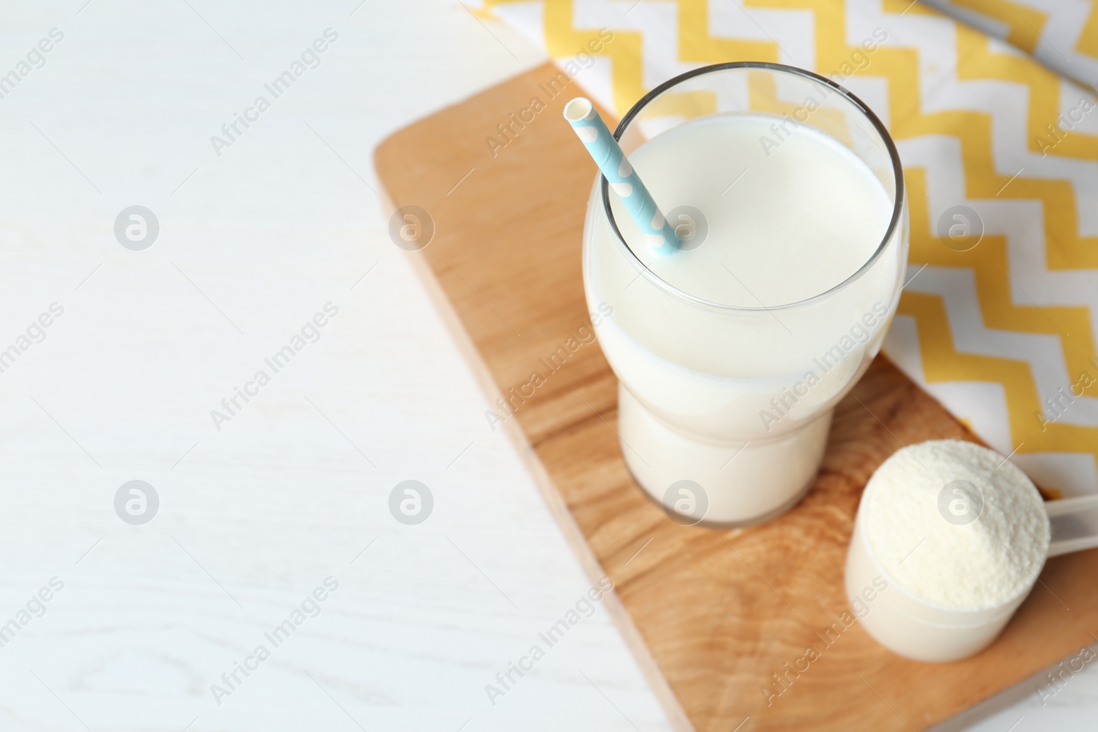 Photo of Protein shake in glass and powder on table. Space for text