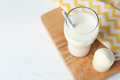 Photo of Protein shake in glass and powder on table. Space for text