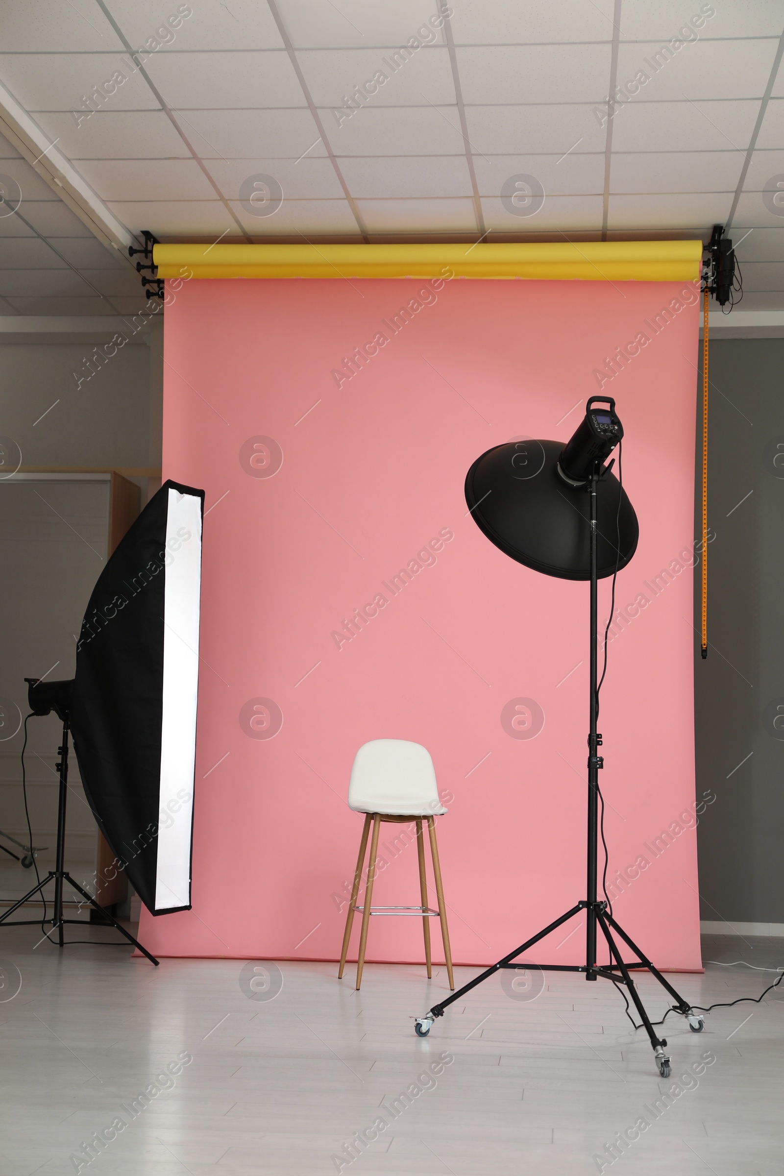 Photo of Pink photo background, workplace and professional lighting equipment in modern studio