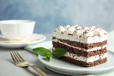 Photo of Tiramisu cake with cup on table against color background, space for text