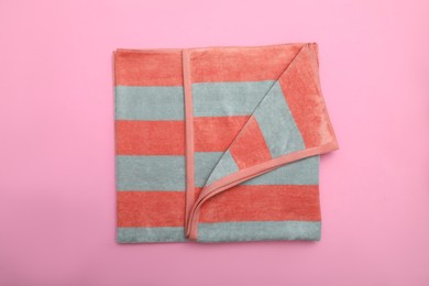 Photo of Folded striped beach towel on pink background, top view