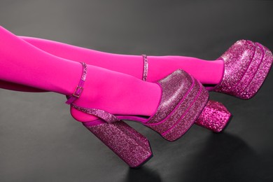 Photo of Woman wearing pink tights and high heeled shoes with platform and square toes on dark grey background, closeup