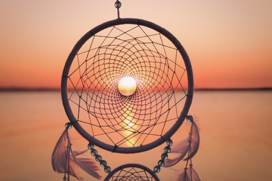 Photo of Beautiful handmade dream catcher near river at sunset