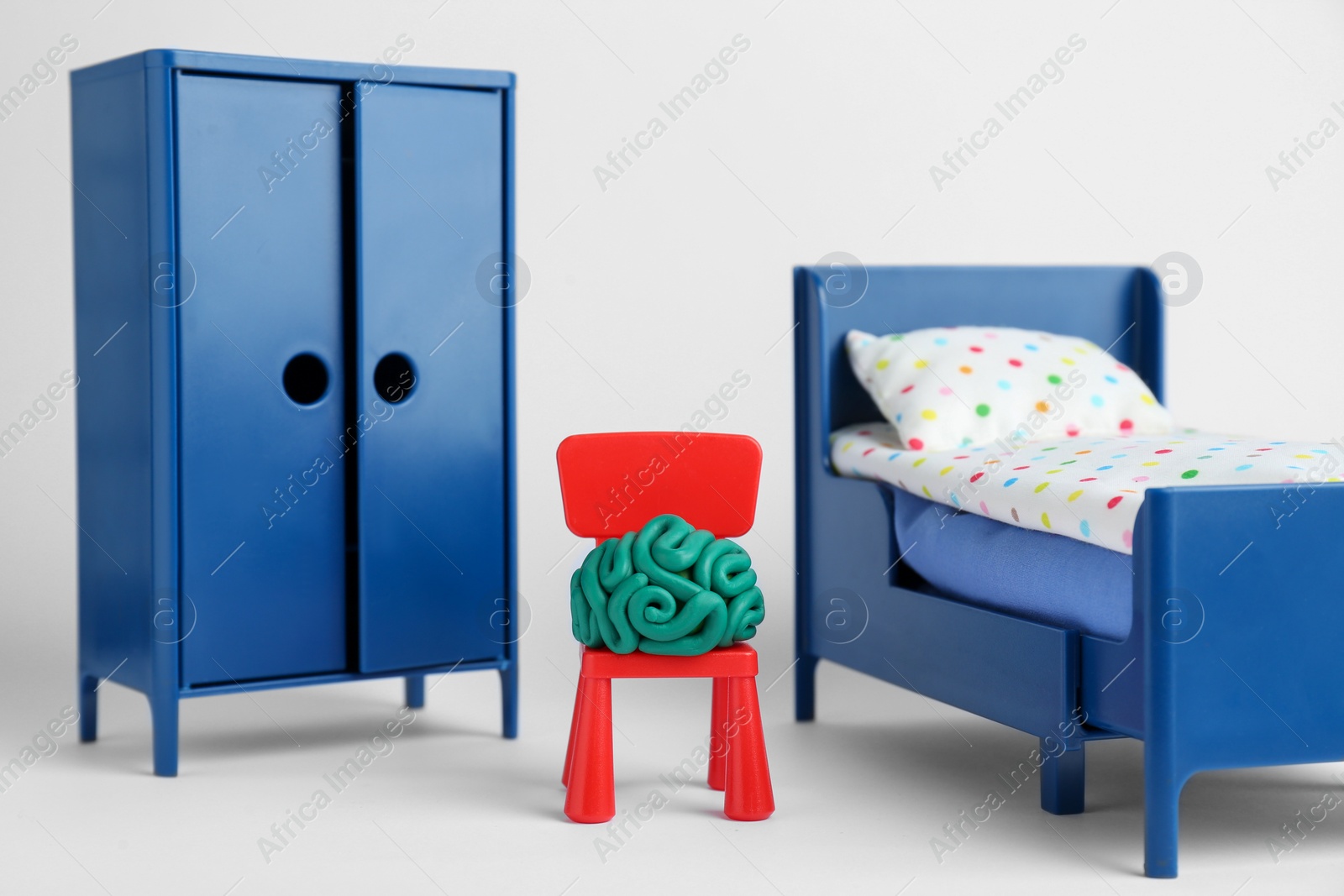 Photo of Brain made of plasticine on chair and mini furniture against white background