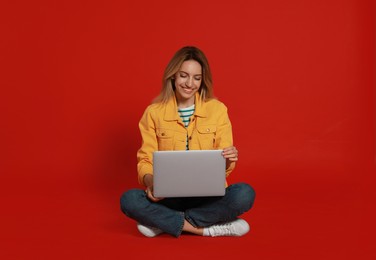 Young woman with modern laptop on red background