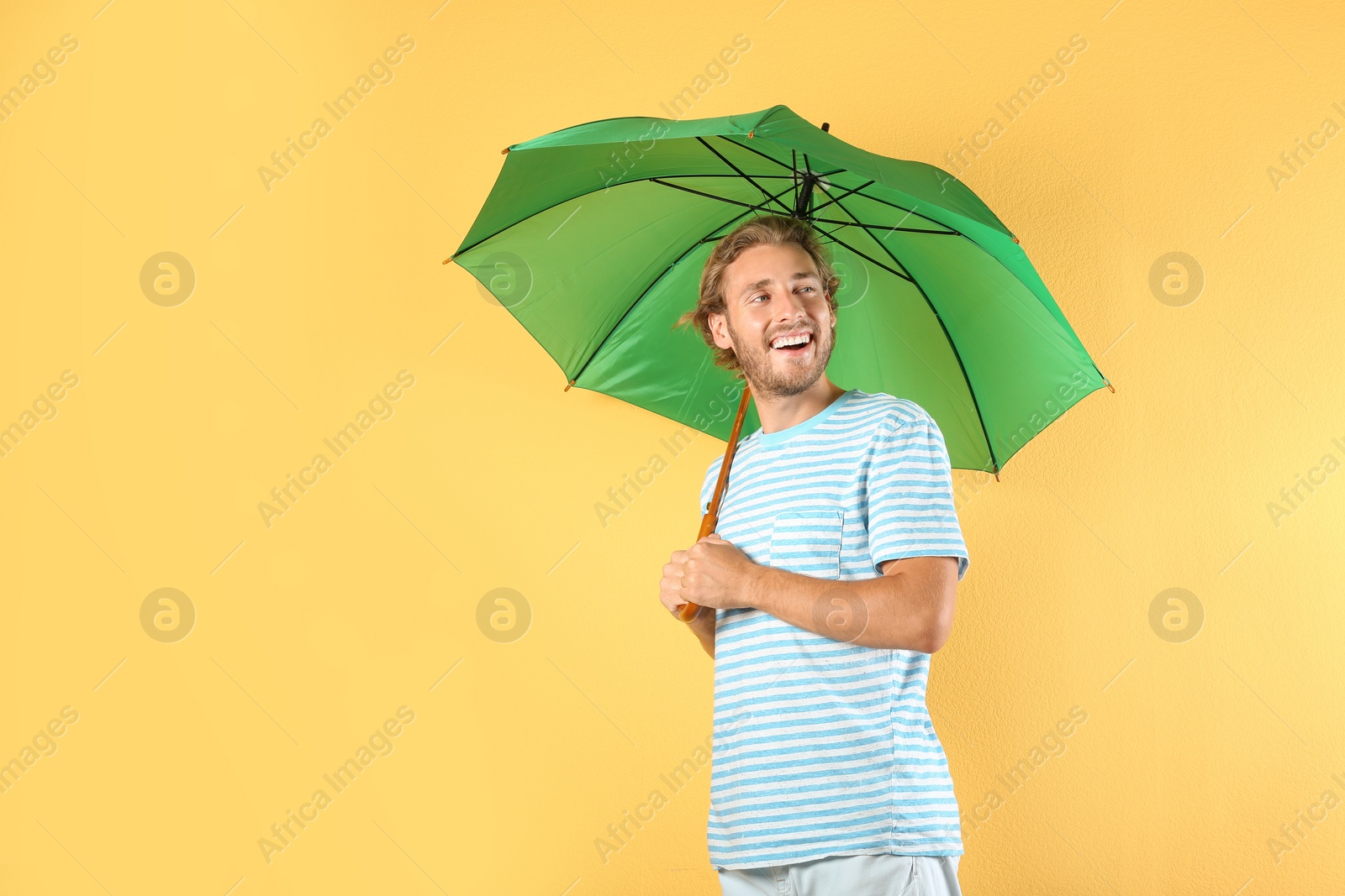 Photo of Man with green umbrella on color background