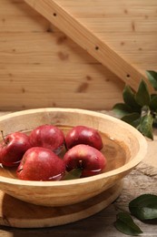 Fresh red apples in bowl with water on wooden table