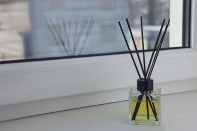 Aromatic reed air freshener on windowsill, space for text