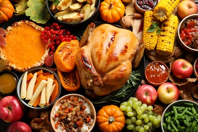 Photo of Traditional Thanksgiving day feast with delicious cooked turkey and other seasonal dishes as background, top view