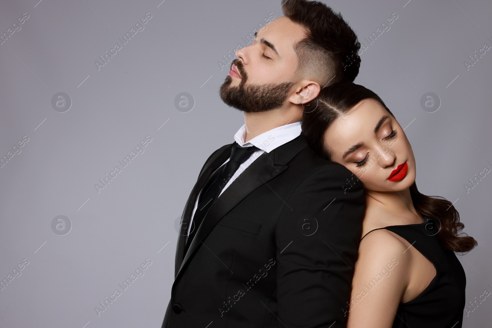 Photo of Handsome bearded man with sexy lady on grey background. Space for text