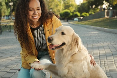 Young African-American woman and her Golden Retriever dog in park