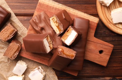 Photo of Tasty chocolate bars and nougat on wooden table, flat lay