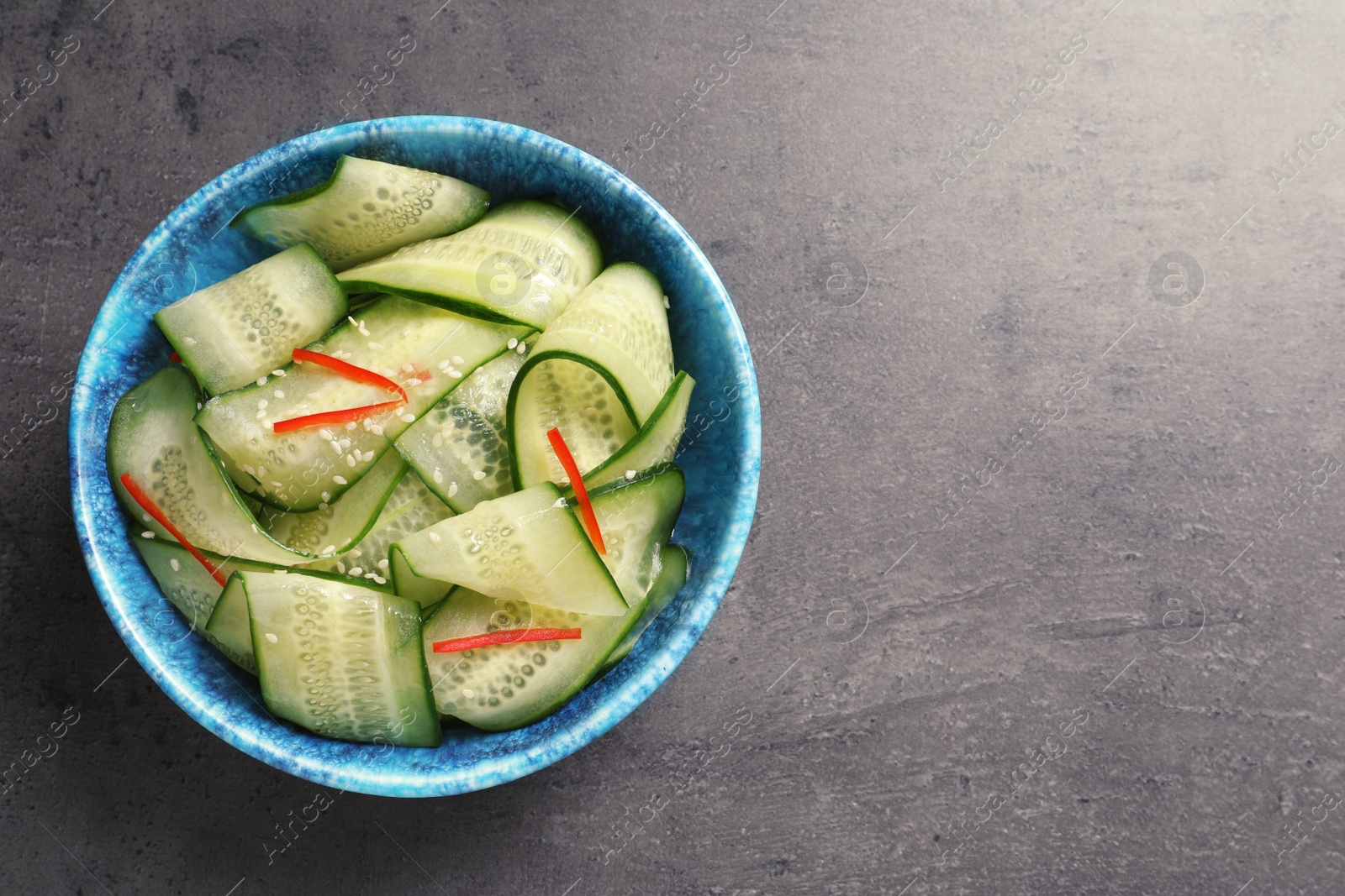 Photo of Dish with fresh cucumber salad on  table, top view. Space for text