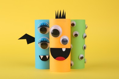 Photo of Spooky paper monsters on yellow background. Halloween decoration