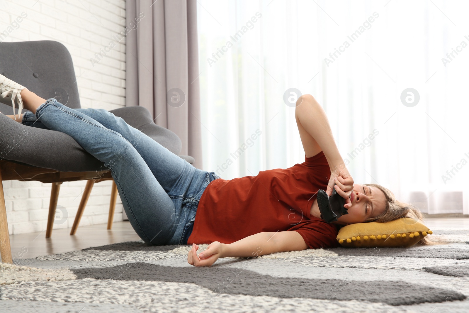 Photo of Lazy young woman playing video game while lying on floor at home