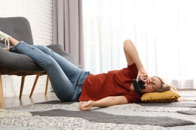 Lazy young woman playing video game while lying on floor at home