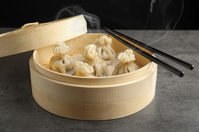 Bamboo steamer with tasty baozi dumplings and chopsticks on table