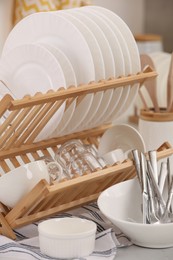 Photo of Drying rack with clean dishes and cutlery on table