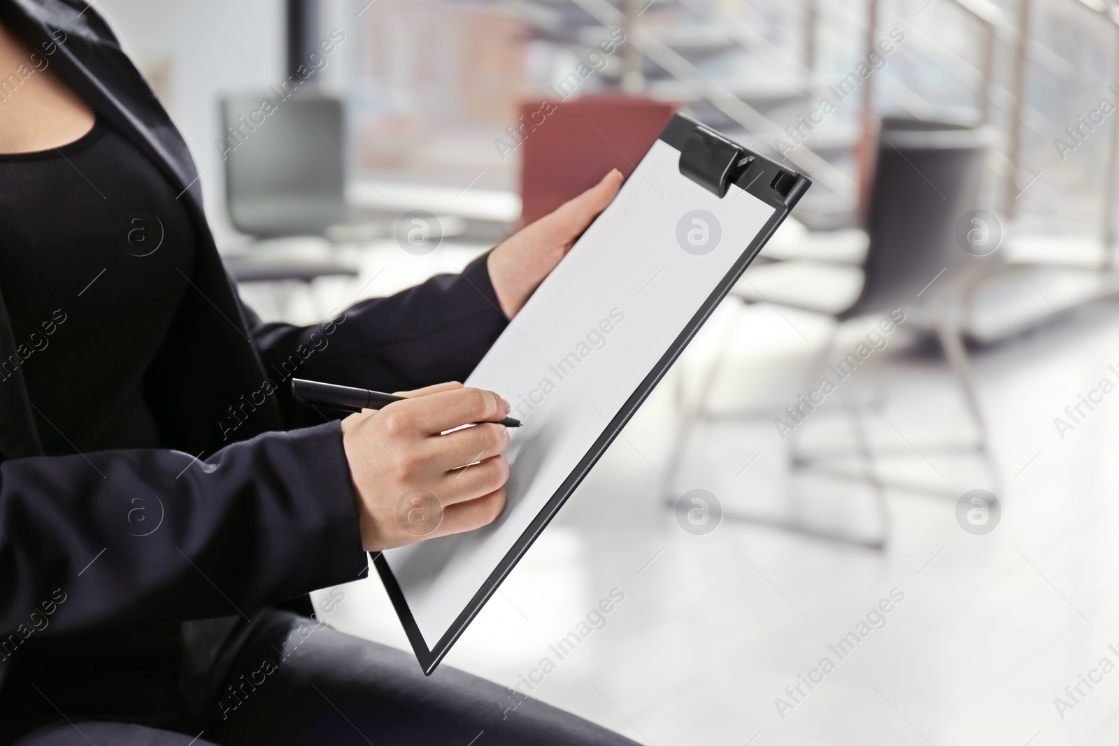 Photo of Psychologist with clipboard prepared for group therapy on blurred background, closeup. Space for text