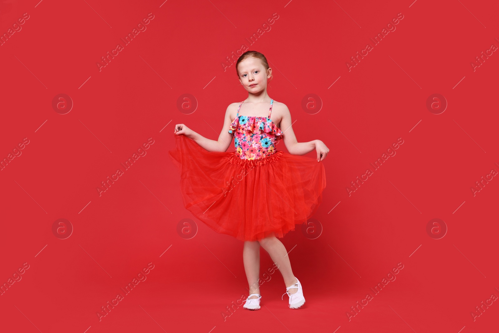 Photo of Cute little girl dancing on red background