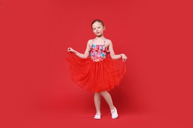 Cute little girl dancing on red background