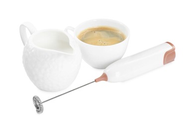 Photo of Mini mixer (milk frother), cup of coffee and pitcher isolated on white