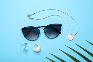 Flat lay composition with stylish sunglasses and accessories on light blue background