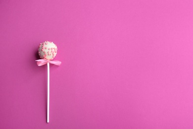 Tasty cake pop with bow on pink background, top view. Space for text