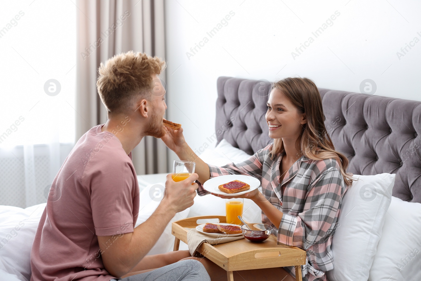 Photo of Happy young couple having romantic breakfast on bed at home