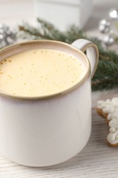 Cup of delicious eggnog on wooden table, closeup