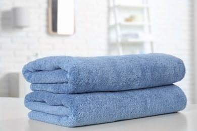 Photo of Stack of fresh towels on table in bathroom, closeup. Space for text