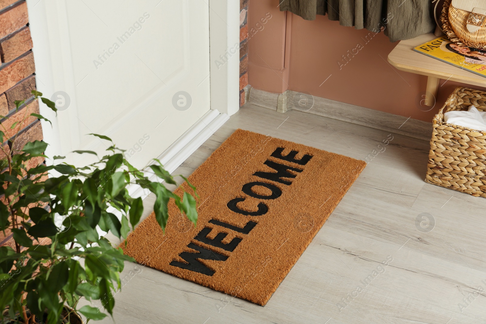 Photo of Door mat with word Welcome on wooden floor in hall