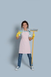 African American woman with yellow broom on grey background