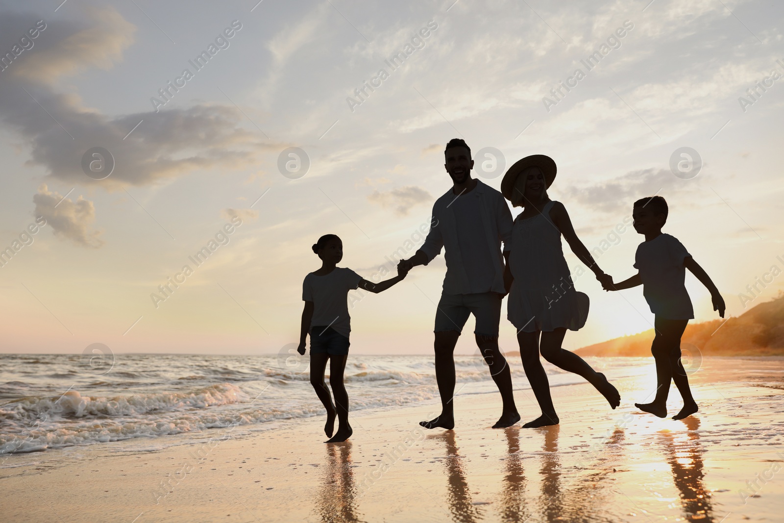 Image of Silhouette of family on seashore at sunset