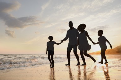 Silhouette of family on seashore at sunset