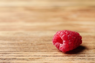 Photo of Delicious ripe raspberry on wooden table, closeup. Space for text