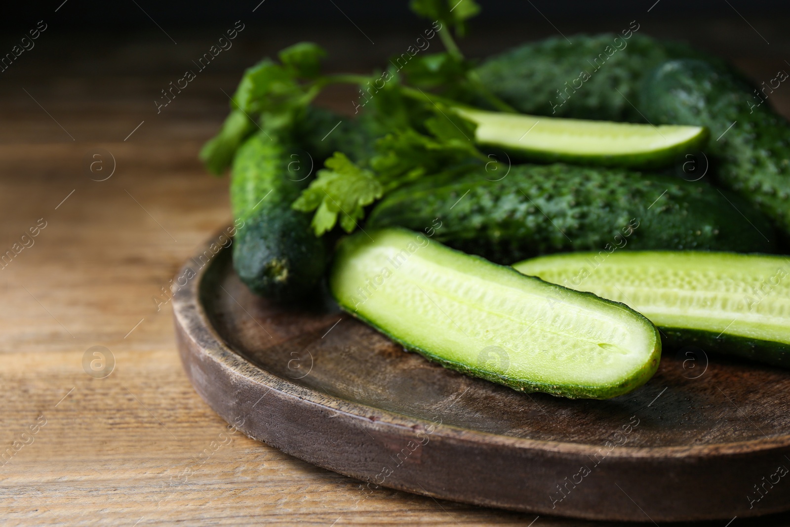 Photo of Fresh ripe cucumbers and parsley on wooden table, closeup